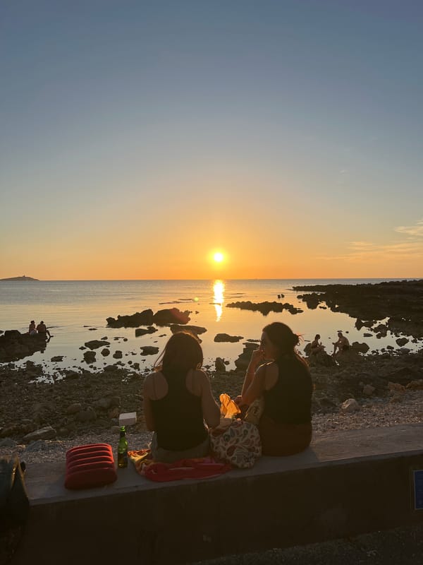Golden hour on a rocky Palermo coastline, people unwinding at sunset