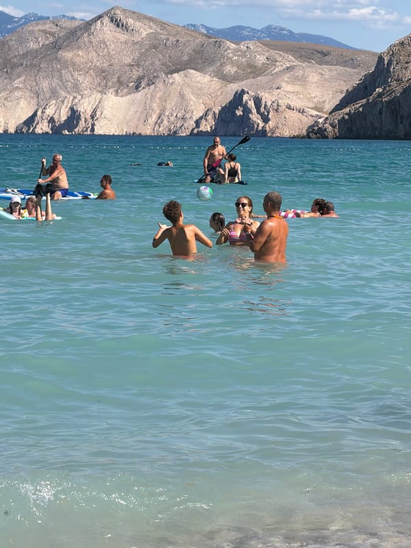 Busy summer day on the pebble beaches of Baška, Croatia