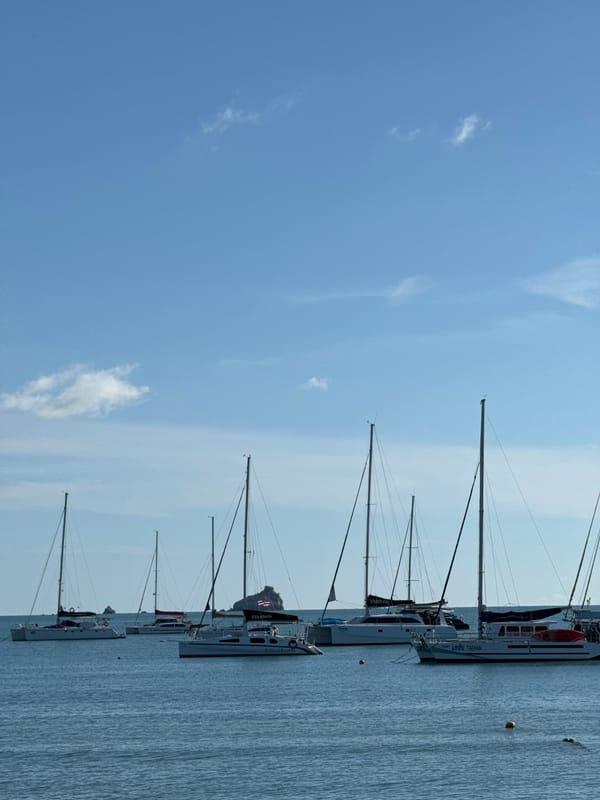 Lazy beach morning with sailboats, lounge chairs, and calm water