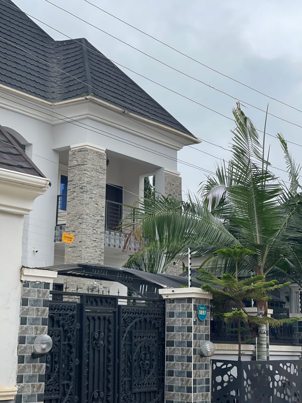 Modern Abuja housing estate with roadside peanut vendor nearby