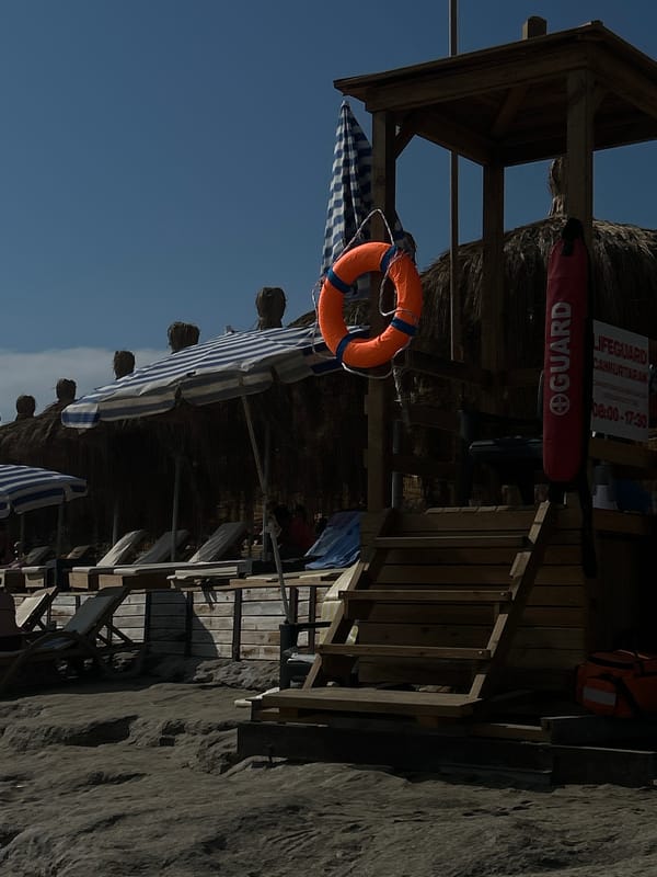Beach visitors skip stones near lifeguard stand during afternoon