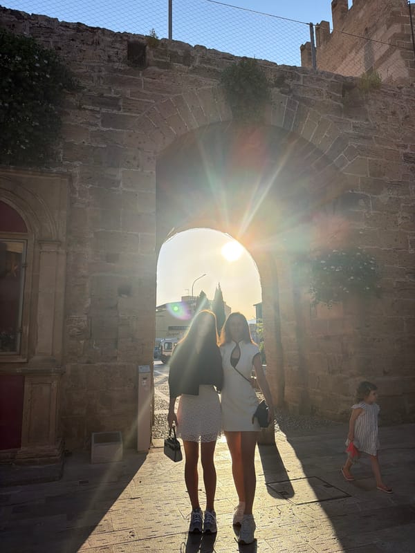 Women photographed walking near medieval walls in Alcúdia, Spain