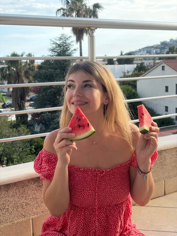 Woman enjoys watermelon snack on Budva balcony with companions