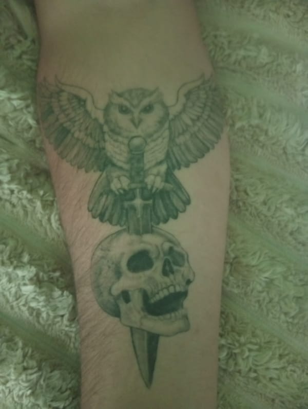 Owl, skull, and dagger tattoo close-up in Ukraine