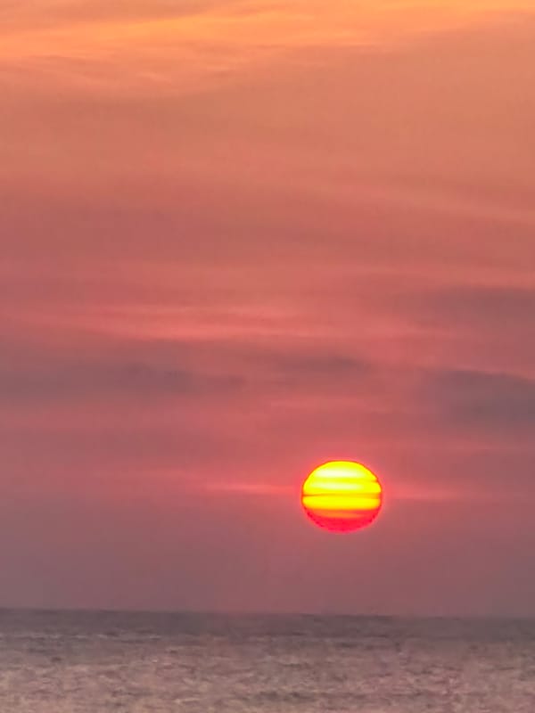 Kuta Beach sunset, warm skies over a calm ocean