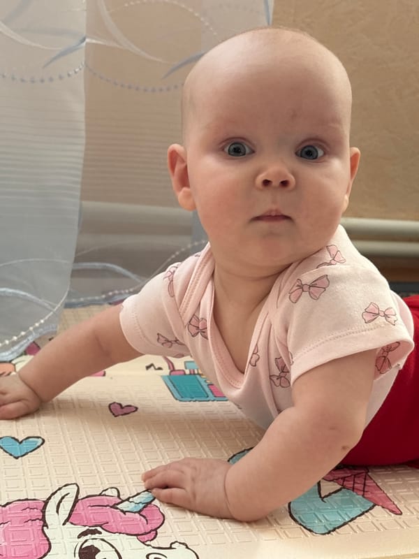 Baby in pink onesie plays on mat in Votkinsk