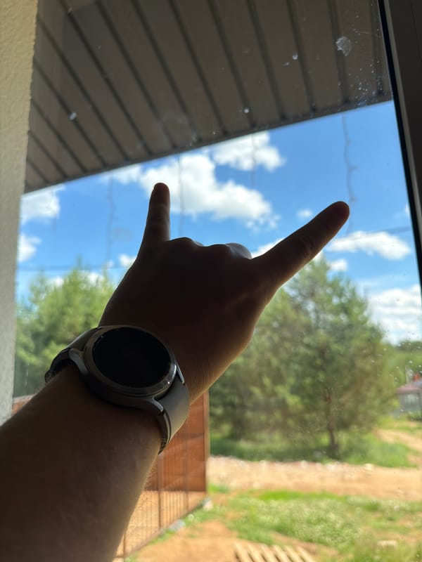 Rock-on gesture and smartwatch near a window in Chaikovsky