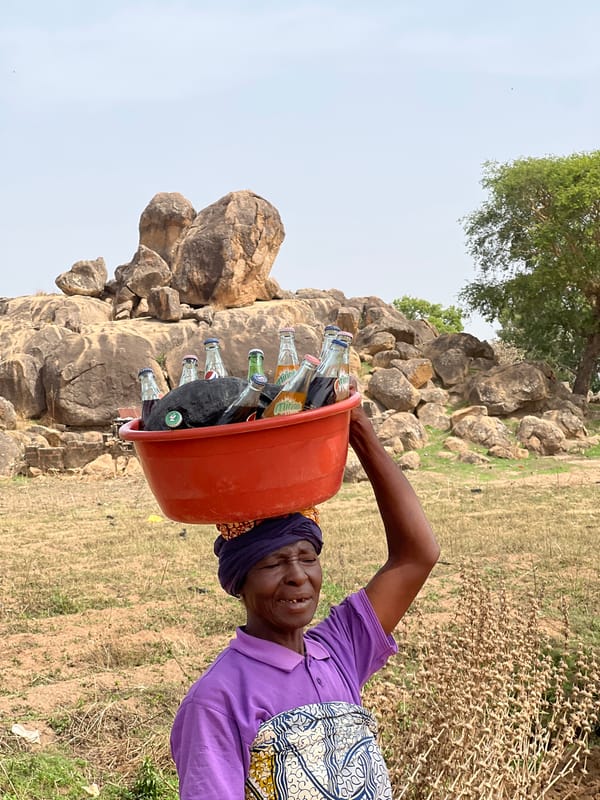 Woman carries bottles in tub on head in Udu