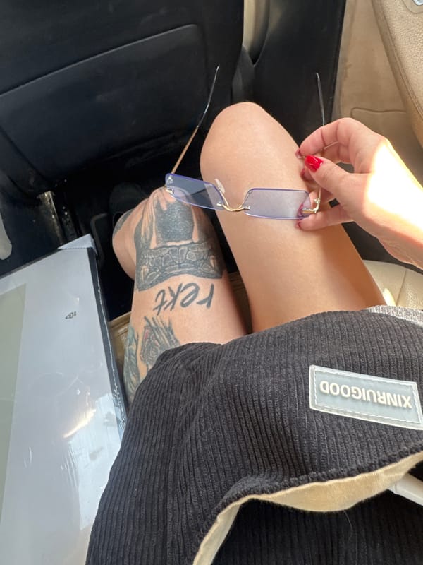 Person with red nails holds glasses in Bat Yam car