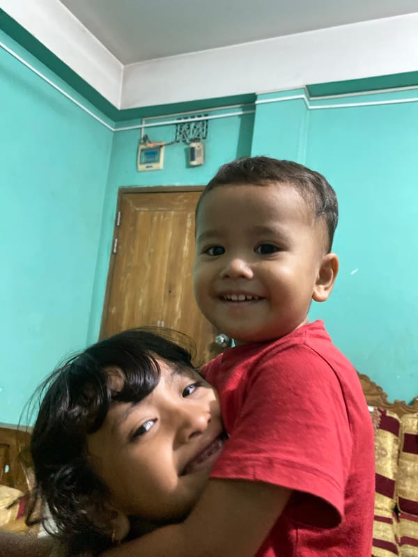 Children share tender moment indoors in Dhaka