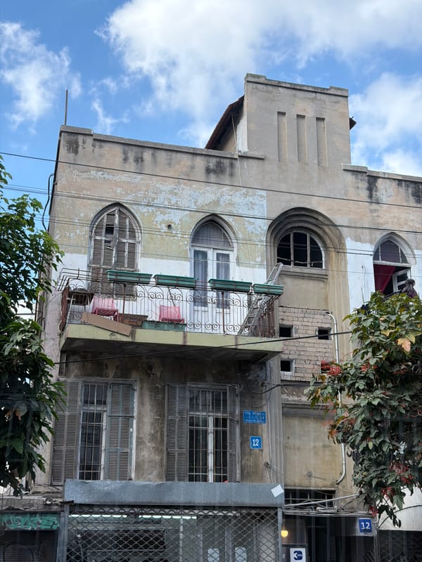 A Tel Aviv block: weathered buildings, parked cars, morning cyclist