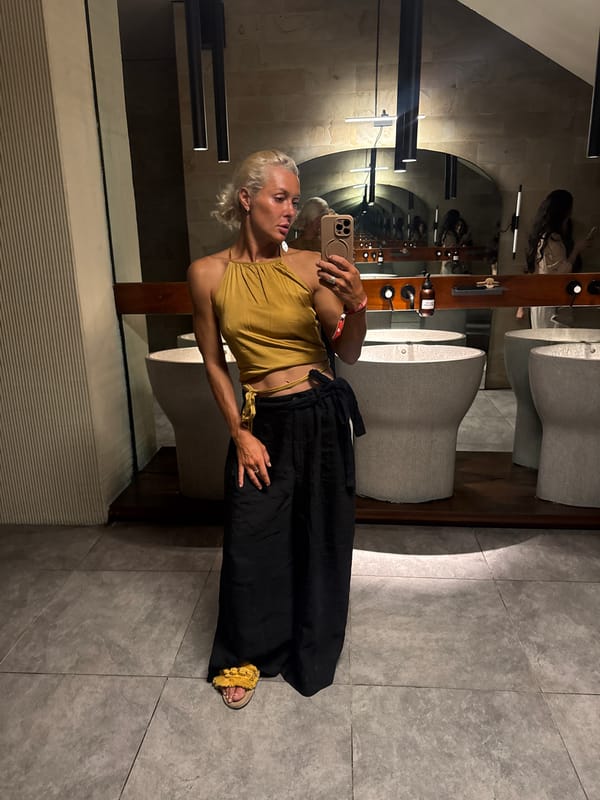 Mirror selfie in a stone-walled bathroom, styled in gold and black.