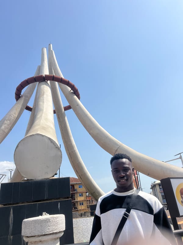 Young men photograph themselves near elephant tusk monument in Onitsha