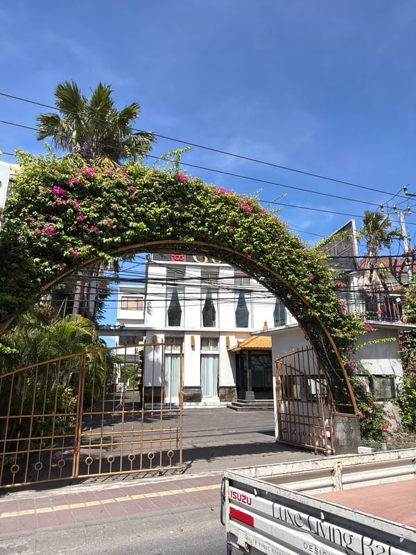 Denpasar street corner: archway, stone pillar, travel agency signage