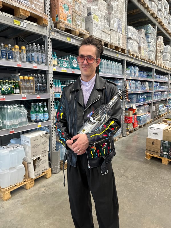 Man with painted jacket holds vodka bottle in Engels store
