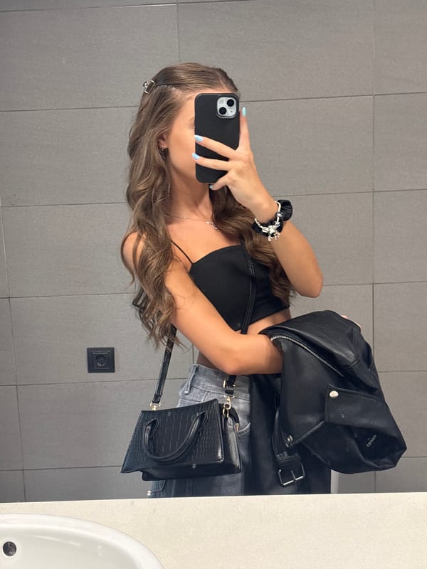Mirror selfie in a public restroom, casual outfit on display.