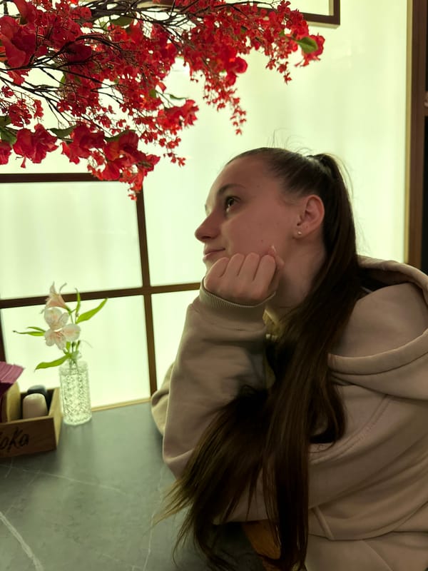 Woman in beige hoodie rests contemplatively at indoor table