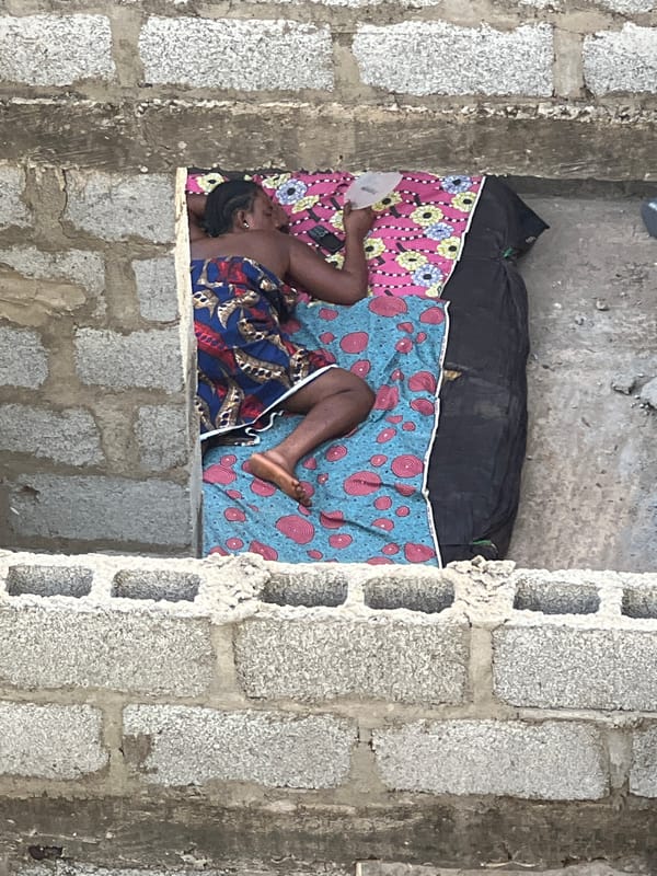 Person rests on bedroll in concrete structure, Abuja
