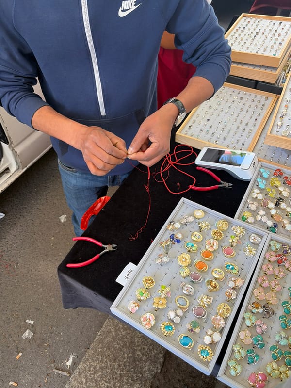 Street vendor works with red string at Milan market