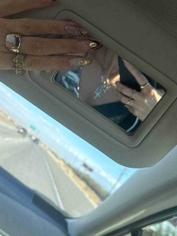 Woman's manicured hands captured in car vanity mirror in Indio