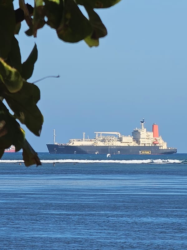 Jukung boats and cargo ships along a Bali morning shoreline