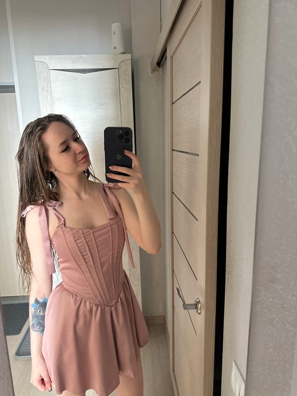 Woman takes mirror selfies in pink dress early morning