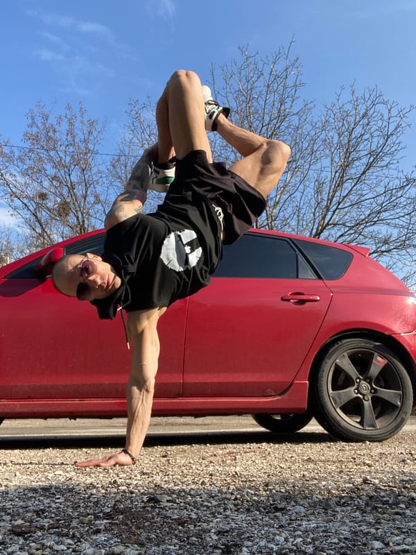 Tattooed man poses with red car in blooming Pleven