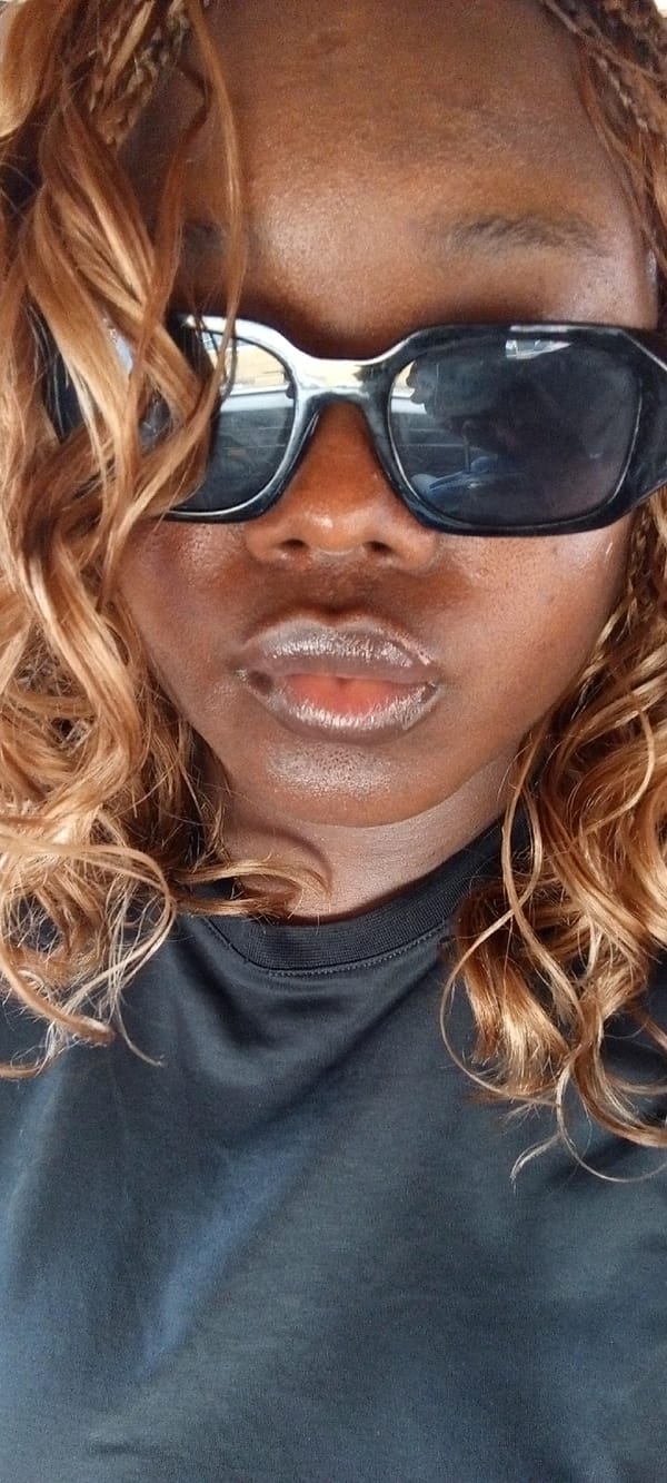 Person with sunglasses photographed in vehicle in Alasia, Nigeria