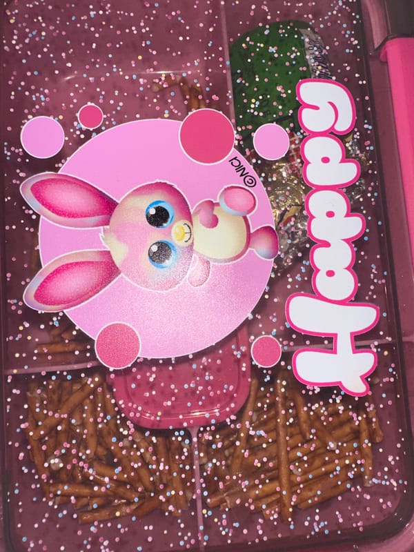 Pink 'Happy' decorated lunchbox with snacks observed