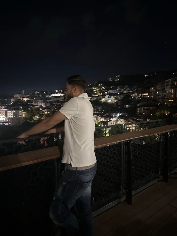 Man spends evening observing illuminated hillside city from balcony