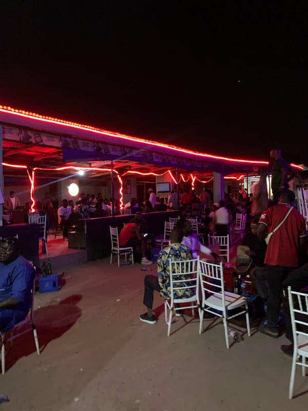 Evening social gathering at red-lit bar in Kabong, Nigeria