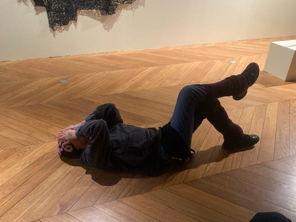 Person resting on floor near artwork in Paris