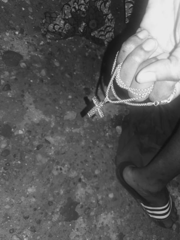 Person poses with cross necklace in Lokoja photography session
