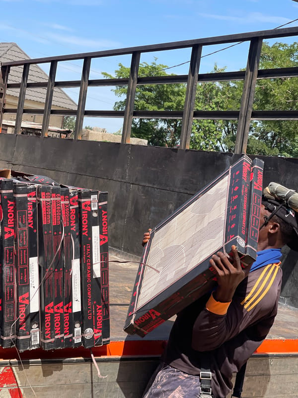 Workers unload ceramic tiles from container in Abuja showroom