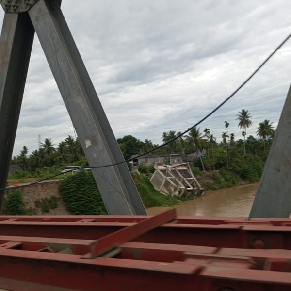 Overloaded truck and collapsed bridge structure along Aceh river corridor