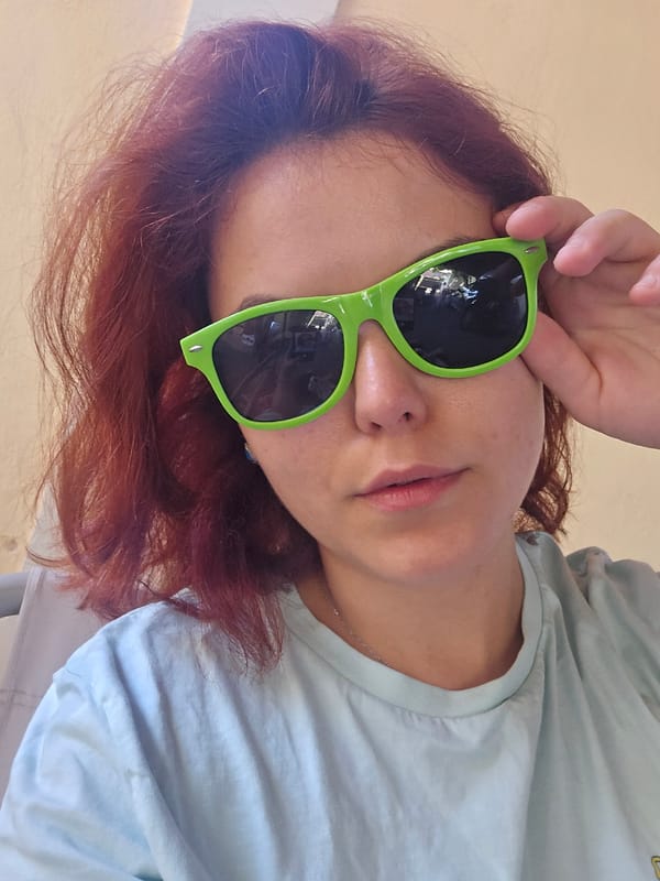 Casual indoor portrait, green sunglasses and light blue tee