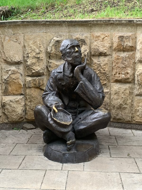 Bronze seated figure with bowl, Kislovodsk stone backdrop