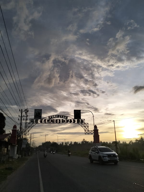 White car travels road under cloudy skies in Tingkeummanyang