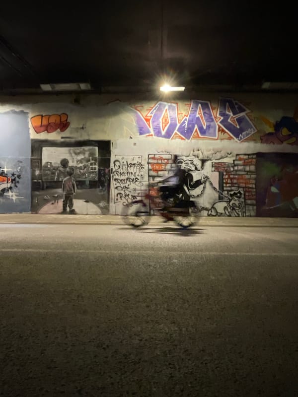 Dense graffiti layers on a Paris alleyway wall at night
