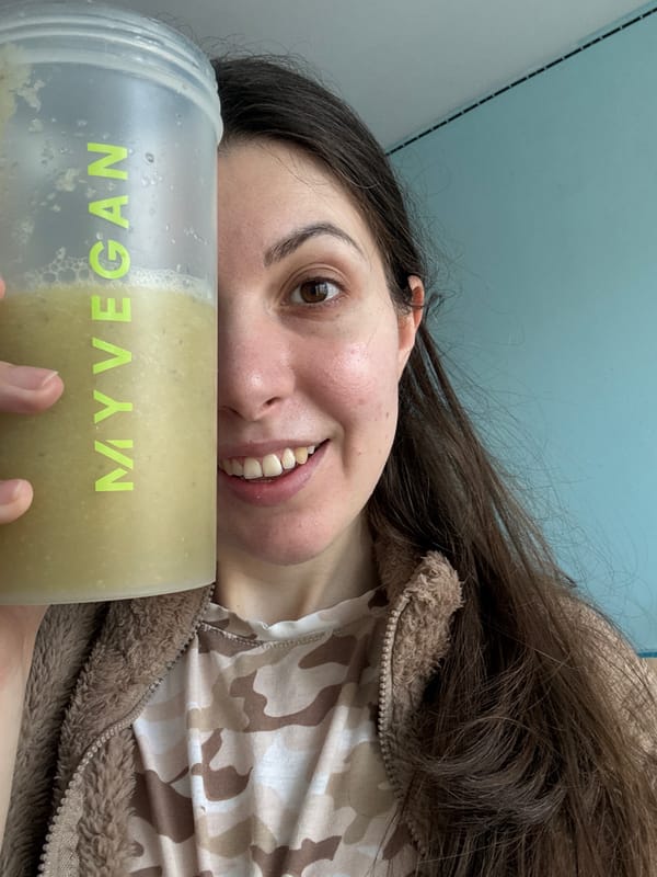 Woman displays protein shake in camouflage hoodie