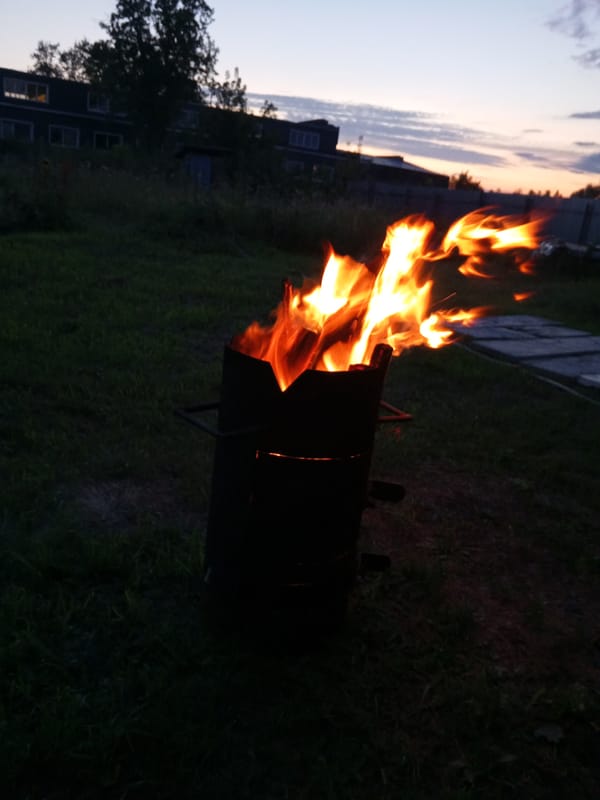 Backyard fire and garden lights at dusk on a summer evening