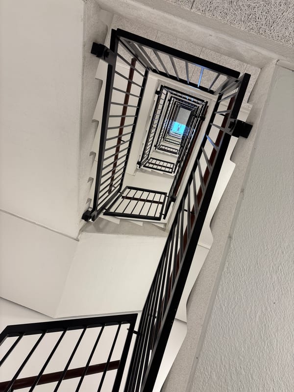 Copenhagen stairwell photographed from below shows white walls, black railings