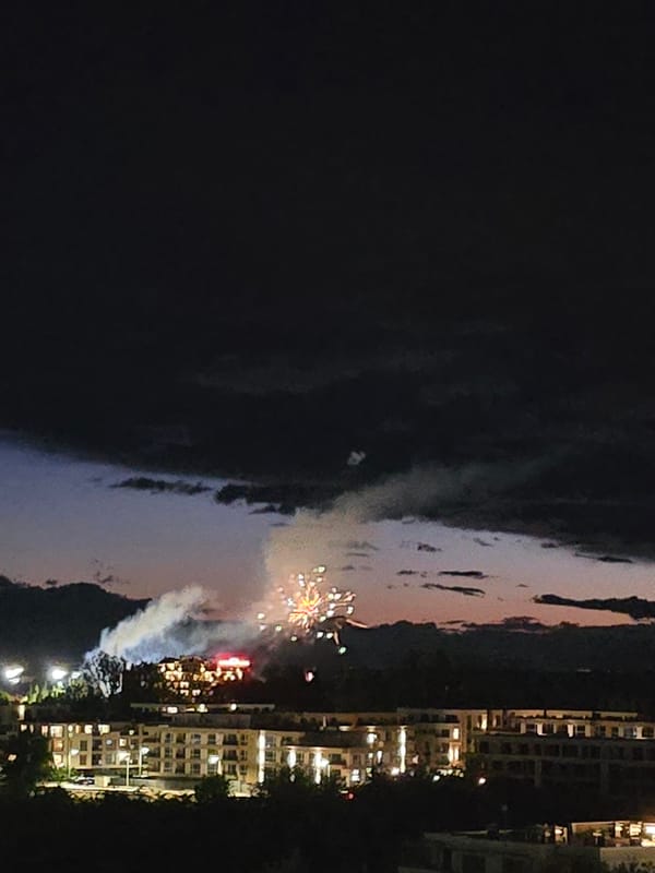 Nighttime fireworks display illuminates unknown city skyline over water