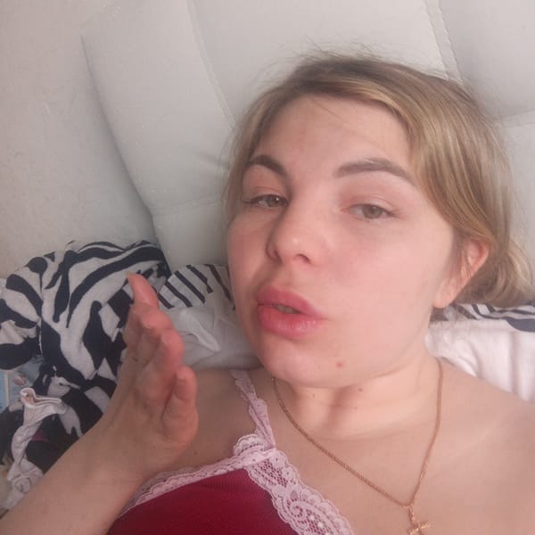 Woman reclining on white surface in red lace top