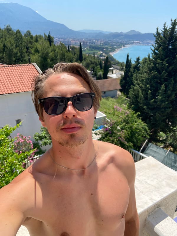 Man poses shirtless with sunglasses on Montenegro balcony
