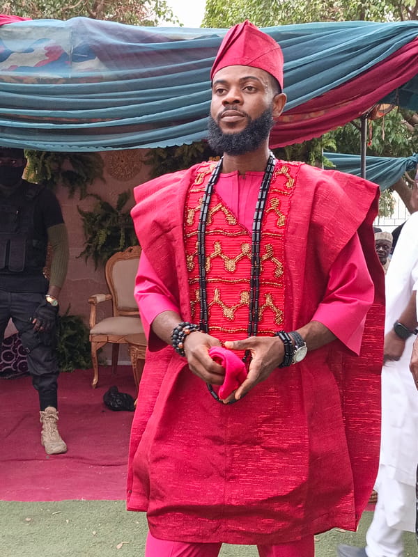 Man in traditional attire attends outdoor ceremony