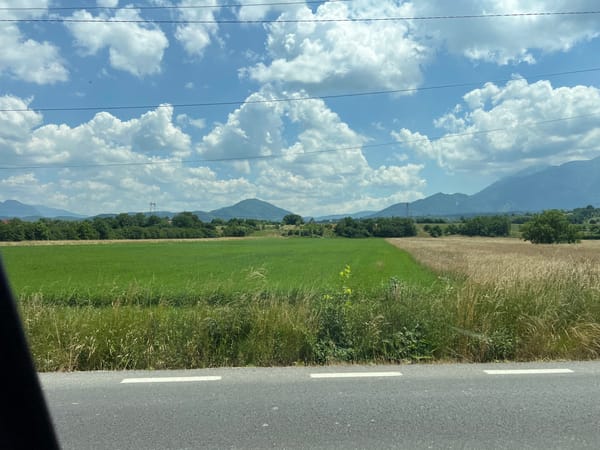Rural highway drive past grasslands, mountains, and a warehouse stop