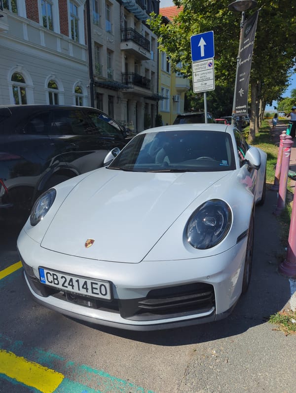 Porsche and Rolls-Royce parked near a shaded walkway in Bulgaria