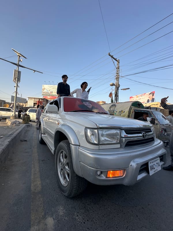 Flag-draped vehicle procession winds through Quetta at sunset