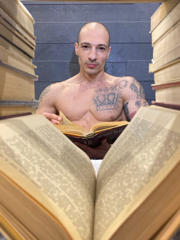 Tattooed man reads book between shelves in Bulgarian library